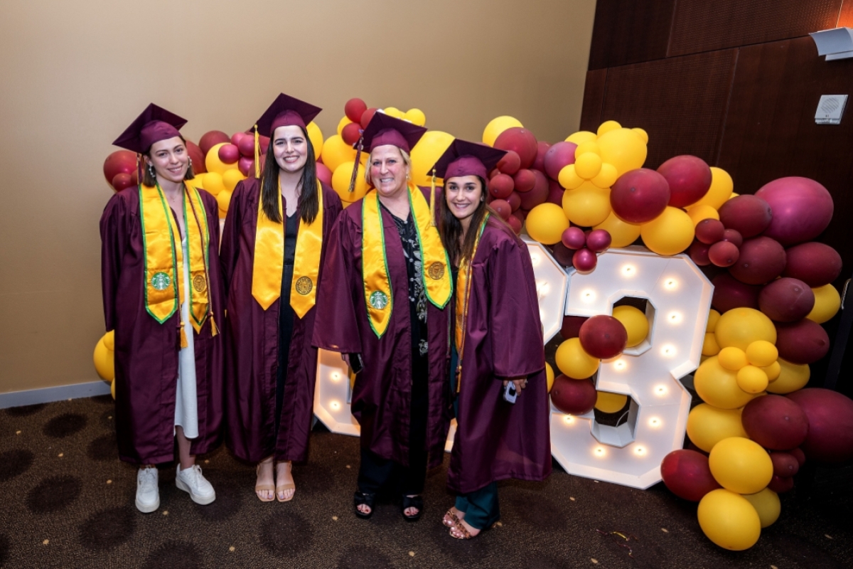 Graduates pose in front of a 2023 sign