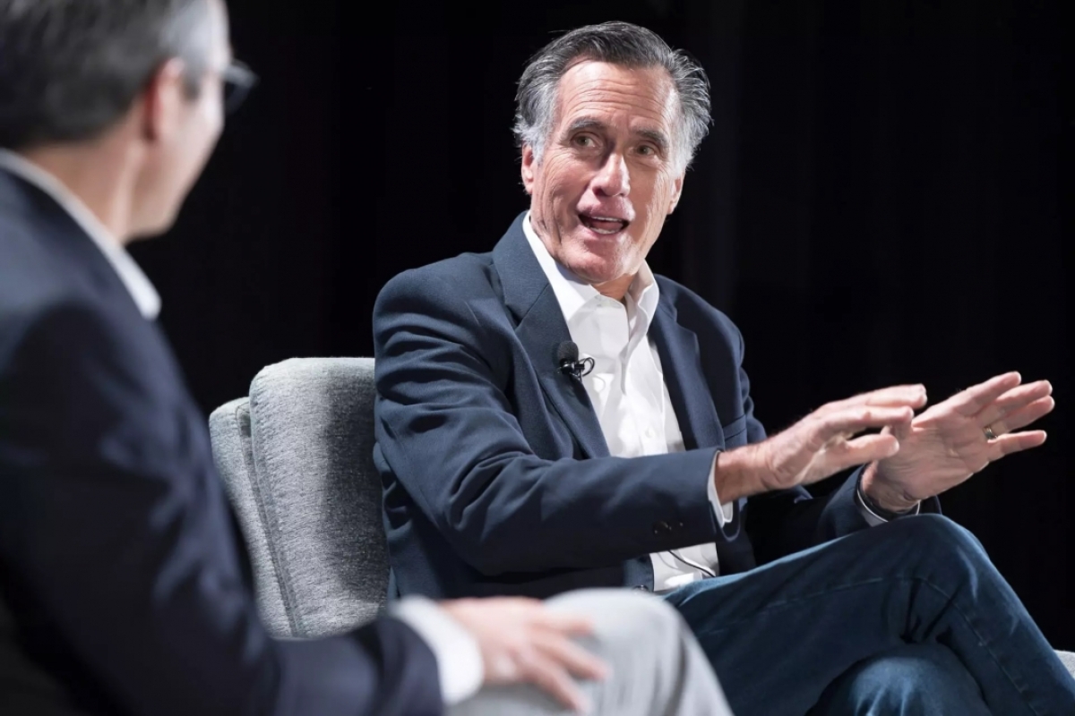 Sen. Mitt Romney talking to man on stage as part of panel