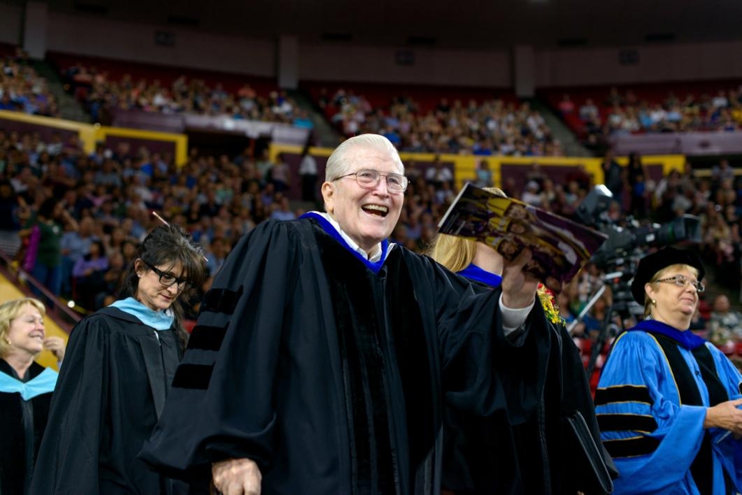 man waving to commencement crowd