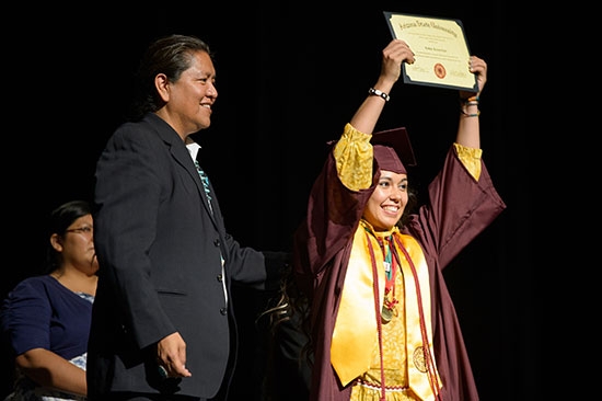 student holding up diploma at convocation