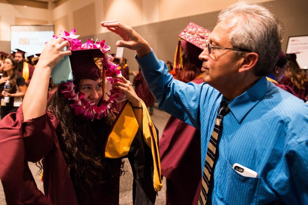 father handing daughter lei at graduation