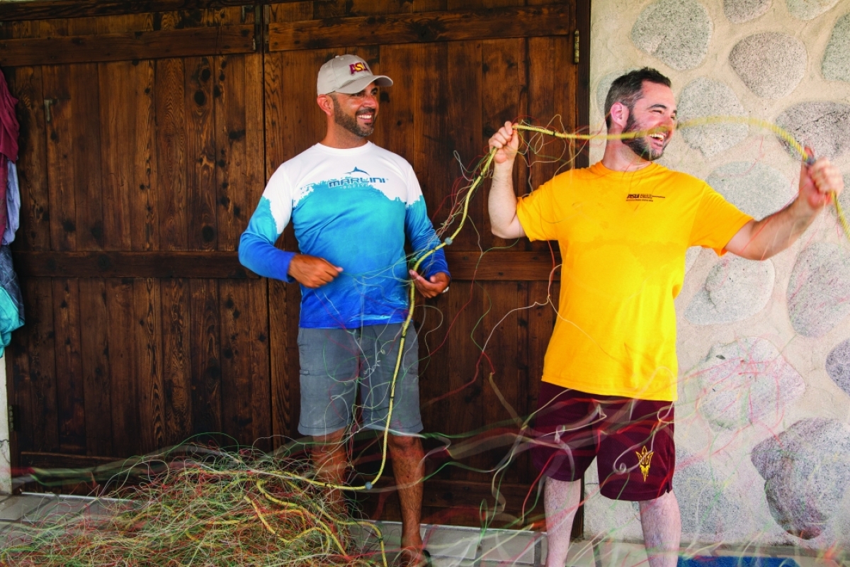 Two men repair a fishing net