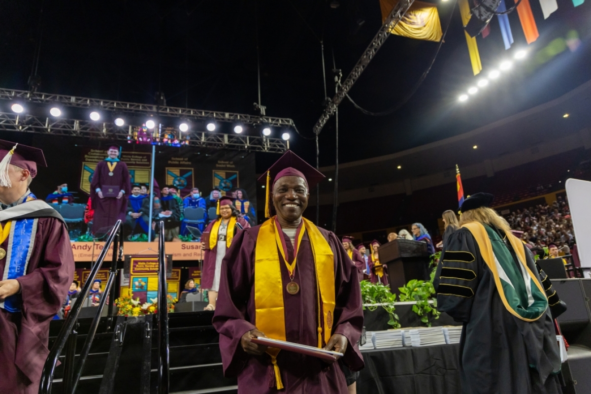 A graduate smiles while descending from the stage at the Watts College spring 2023 convocation