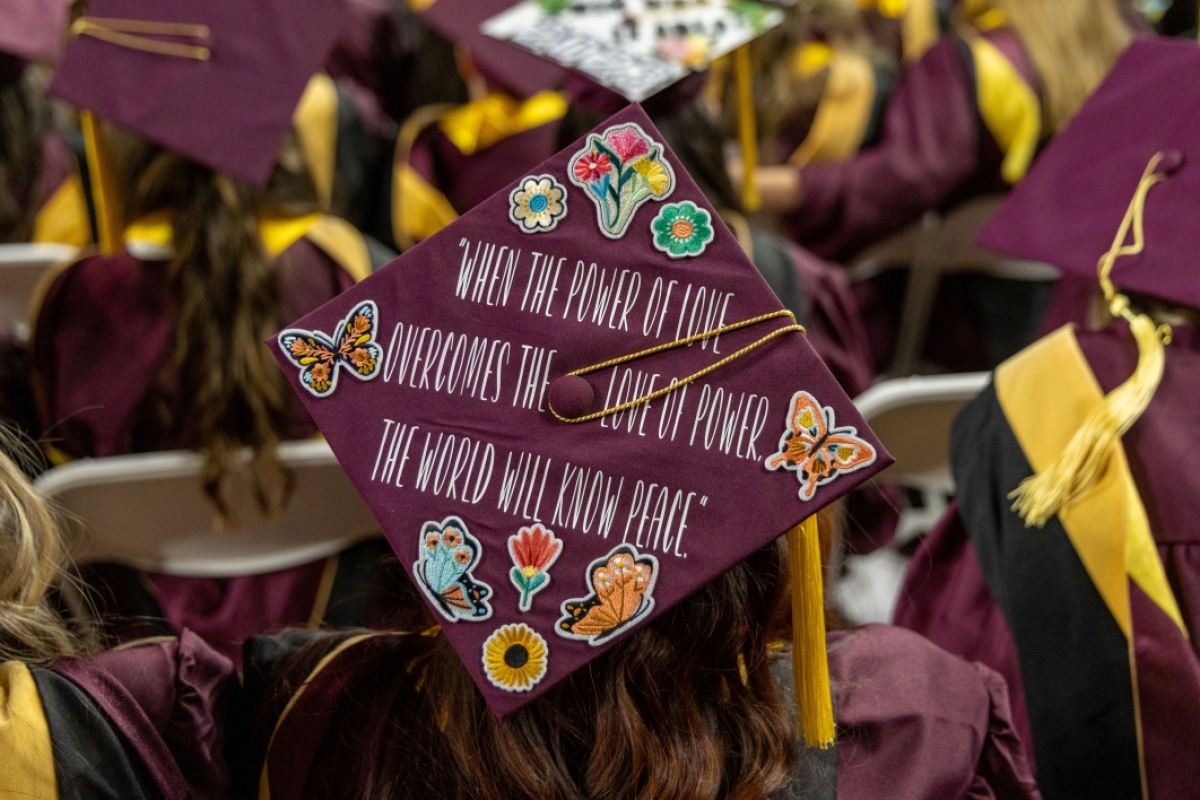 A close-up photo of a mortarboard with a message of peace.