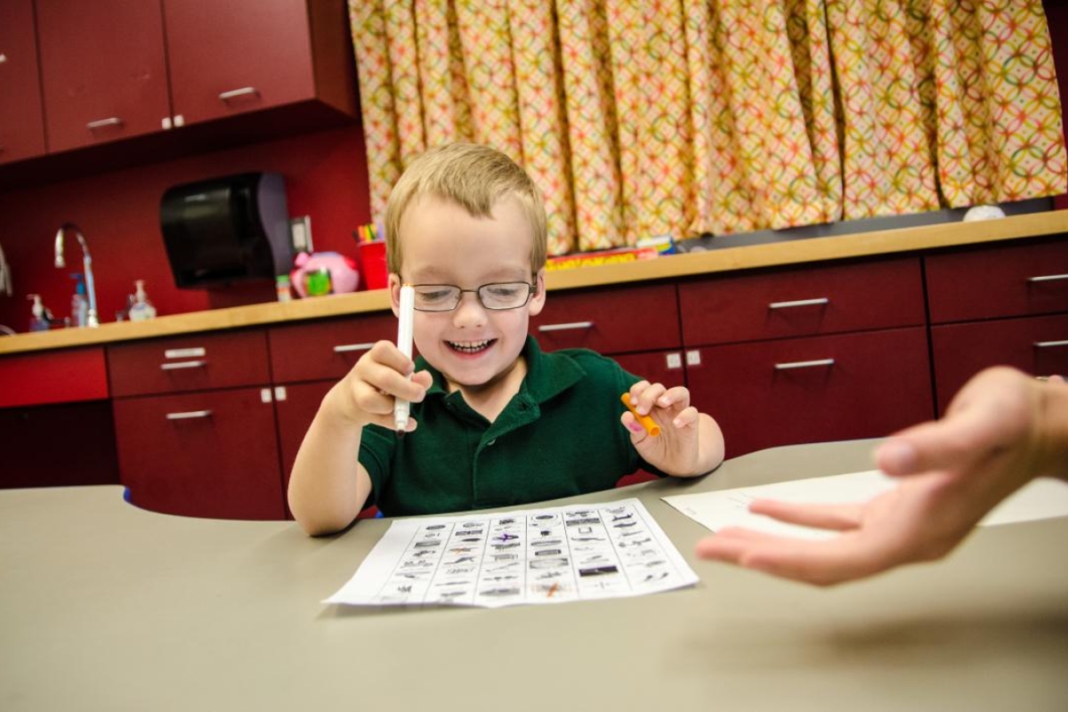 young boy learning words at a table