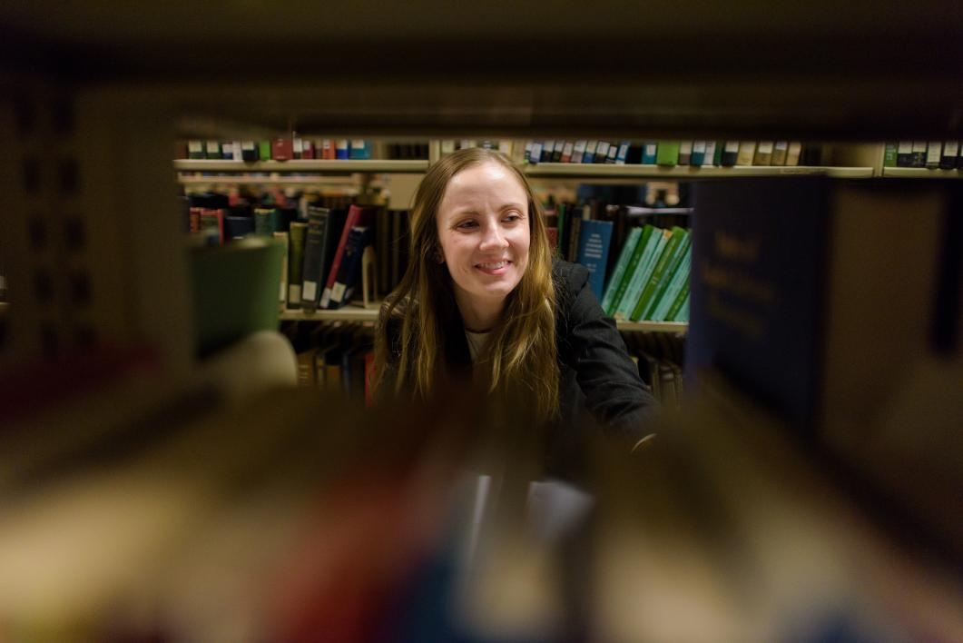 woman looks at bookshelf in library