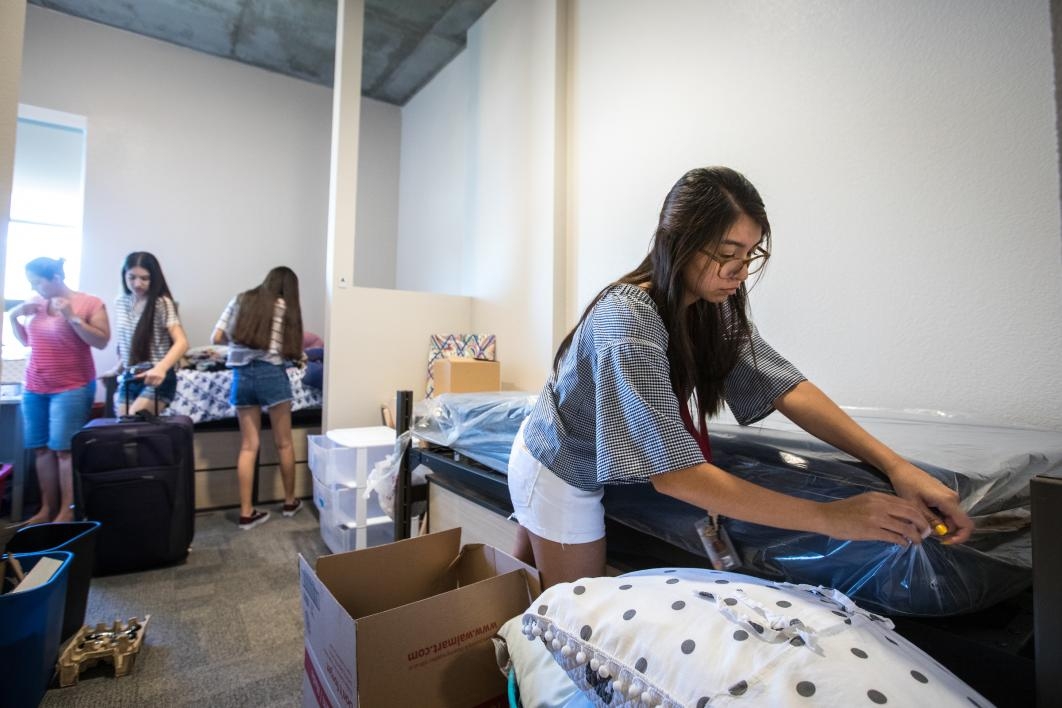A student makes her bed at the dorm