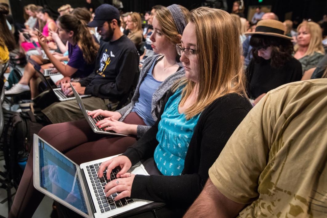 A student works on a laptop in an audience