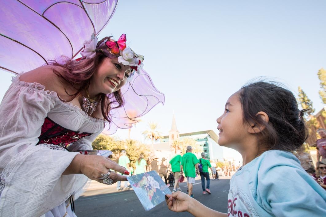 woman dressed as a fairy handing a card to a girl