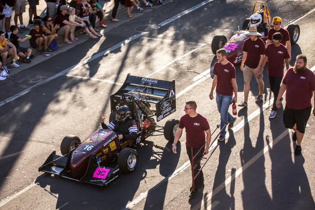 students marching in parade with Formula SAE car
