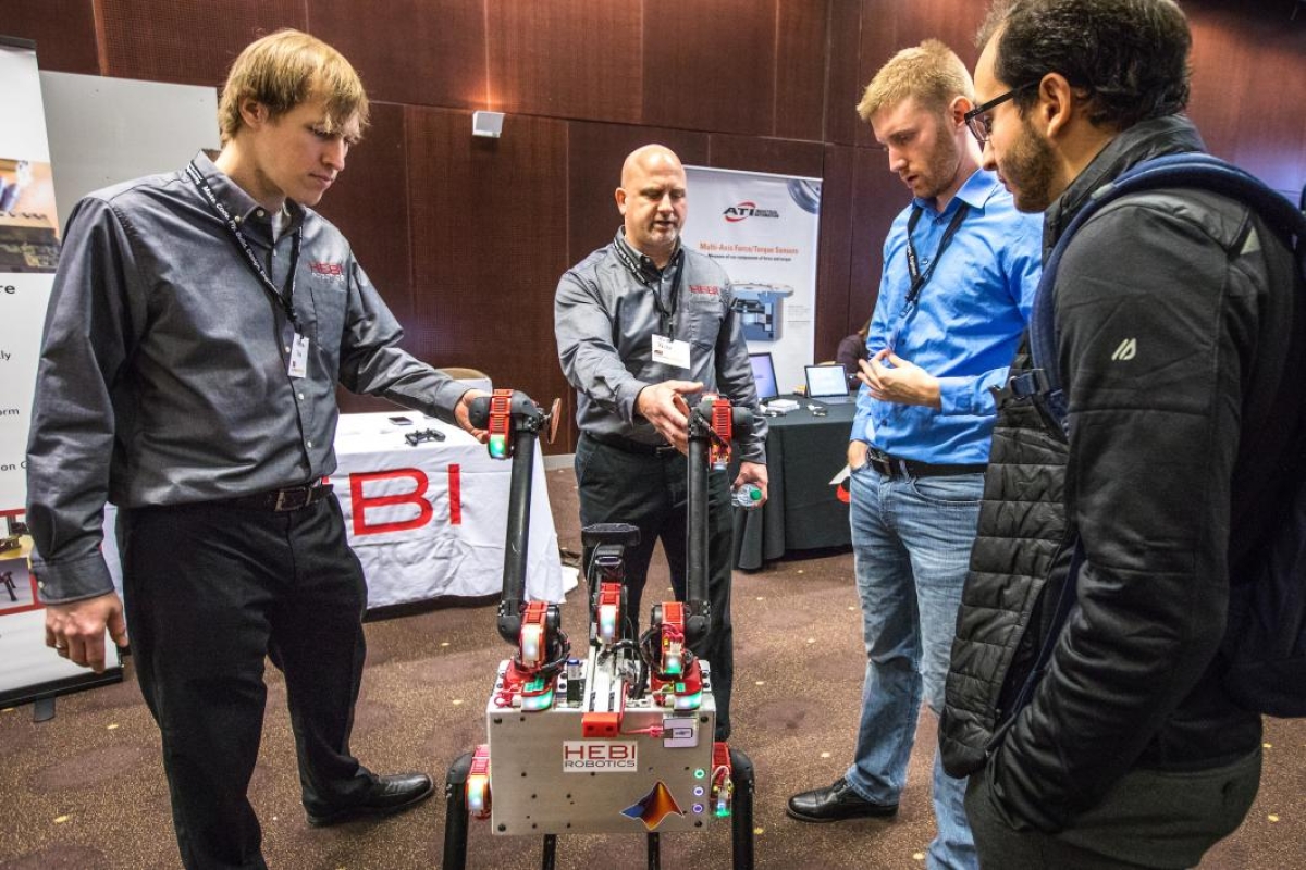 Men demonstrate a robot at a symposium