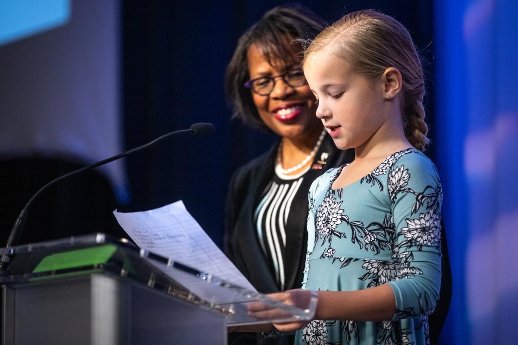 A little girl reads her essay onstage