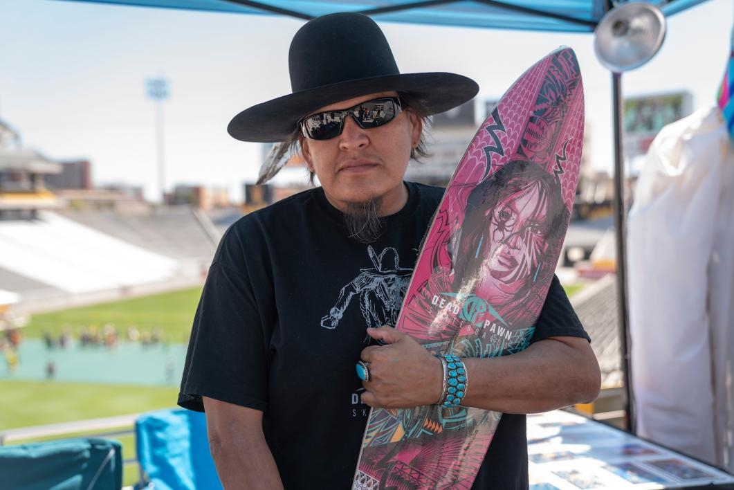 A vendor holds up a skateboard at the ASU Pow Wow