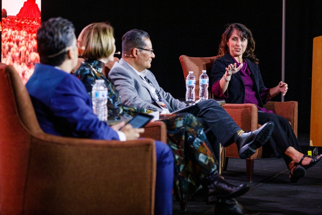 A woman speaks to fellow panel members on a stage.
