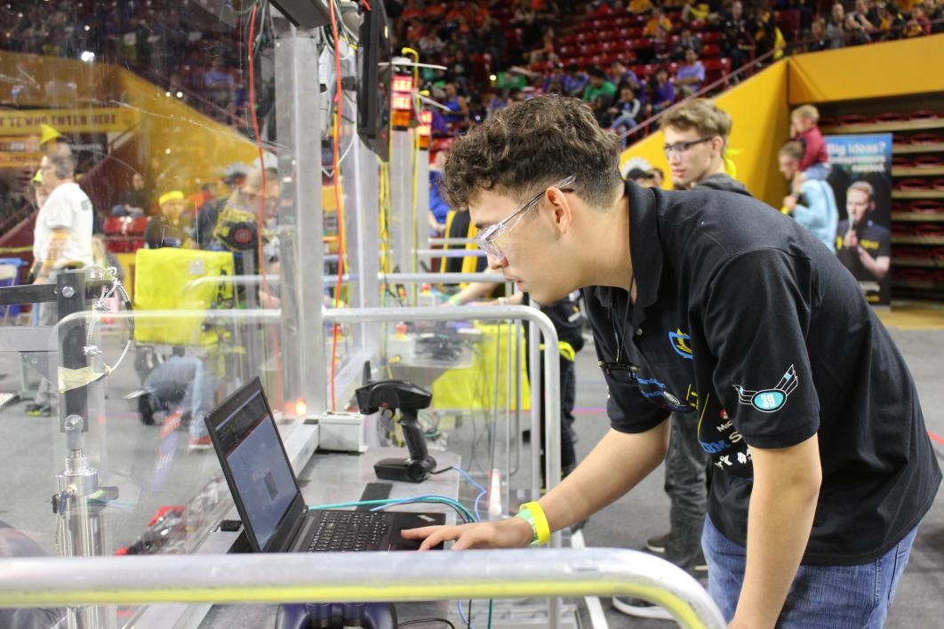 A student looks at a laptop to check on robot controls