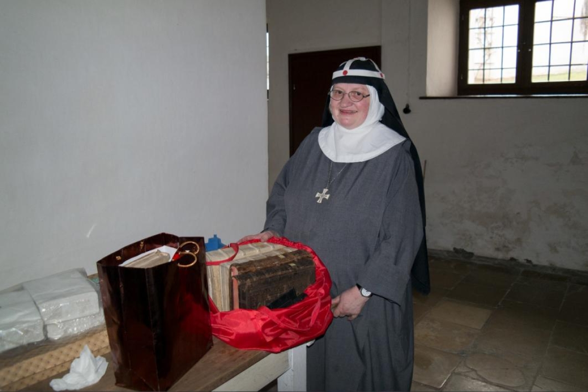 nun next to table full of old books in shopping bags