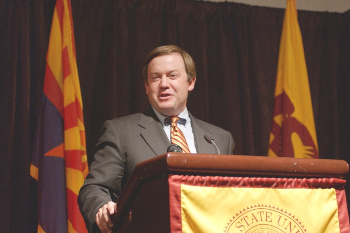 Man speaking behind a lectern with the Arizona State University seal on it.