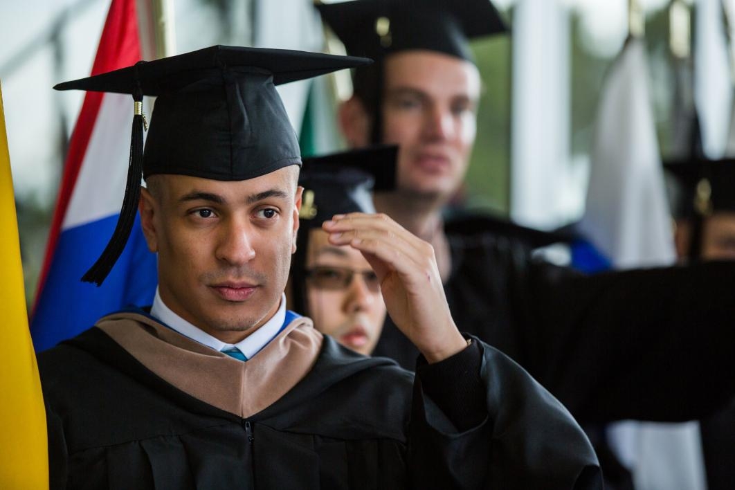 A student adjusts his graduation cap.