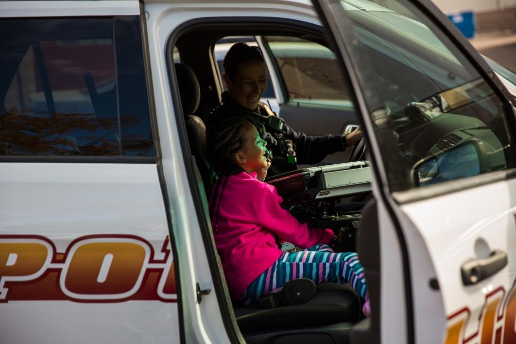 child sitting in front of police car