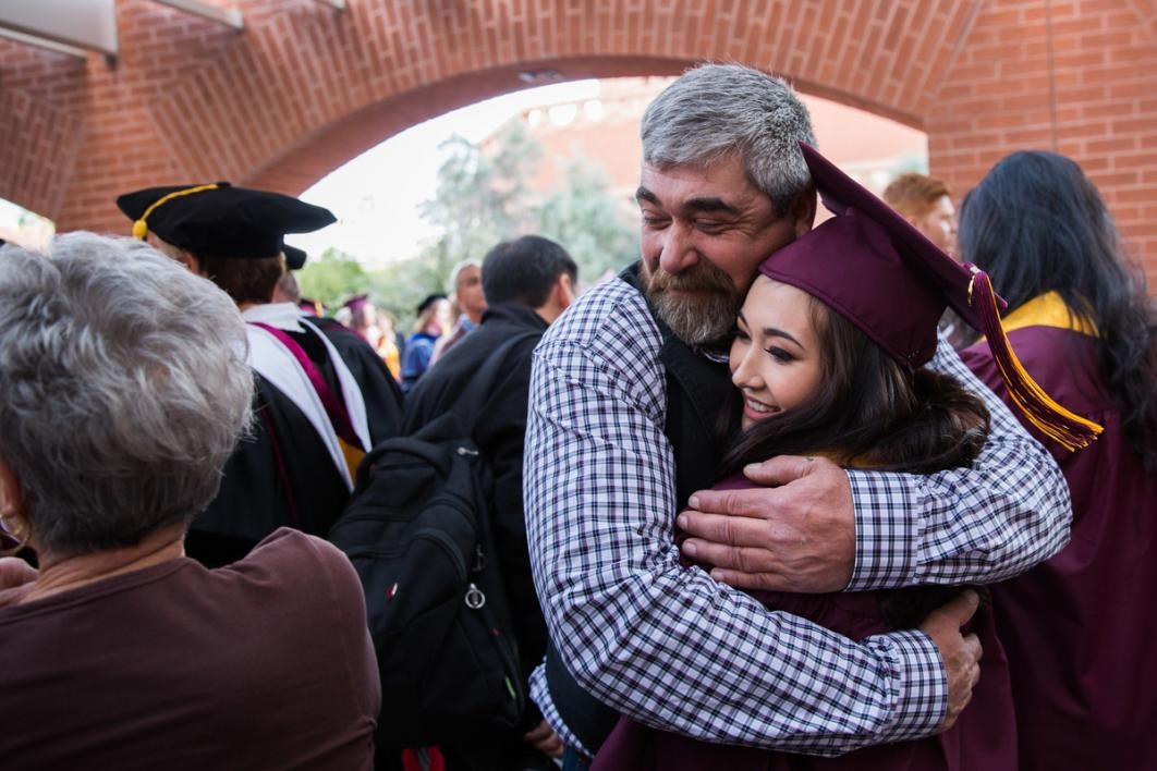 Graduate gets a hug from a man.
