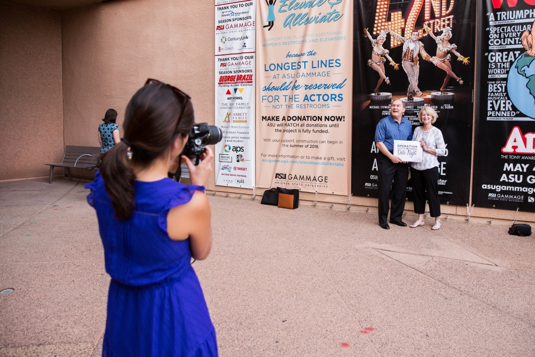 Couple pose for photo in front of Broadway poster