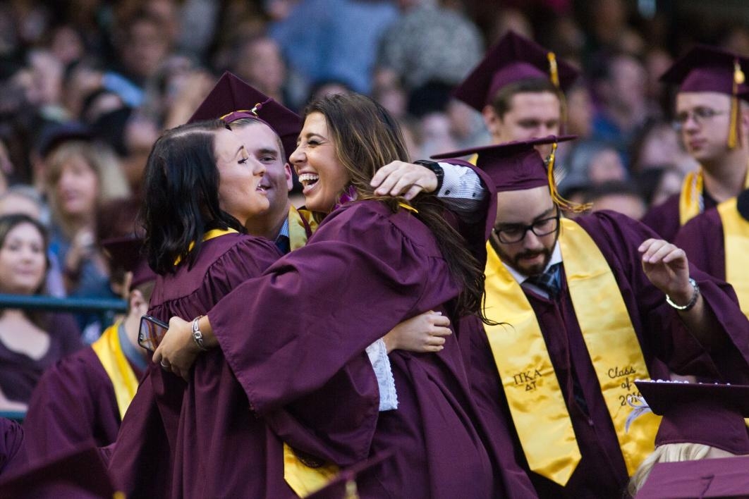 students hugging at commencement