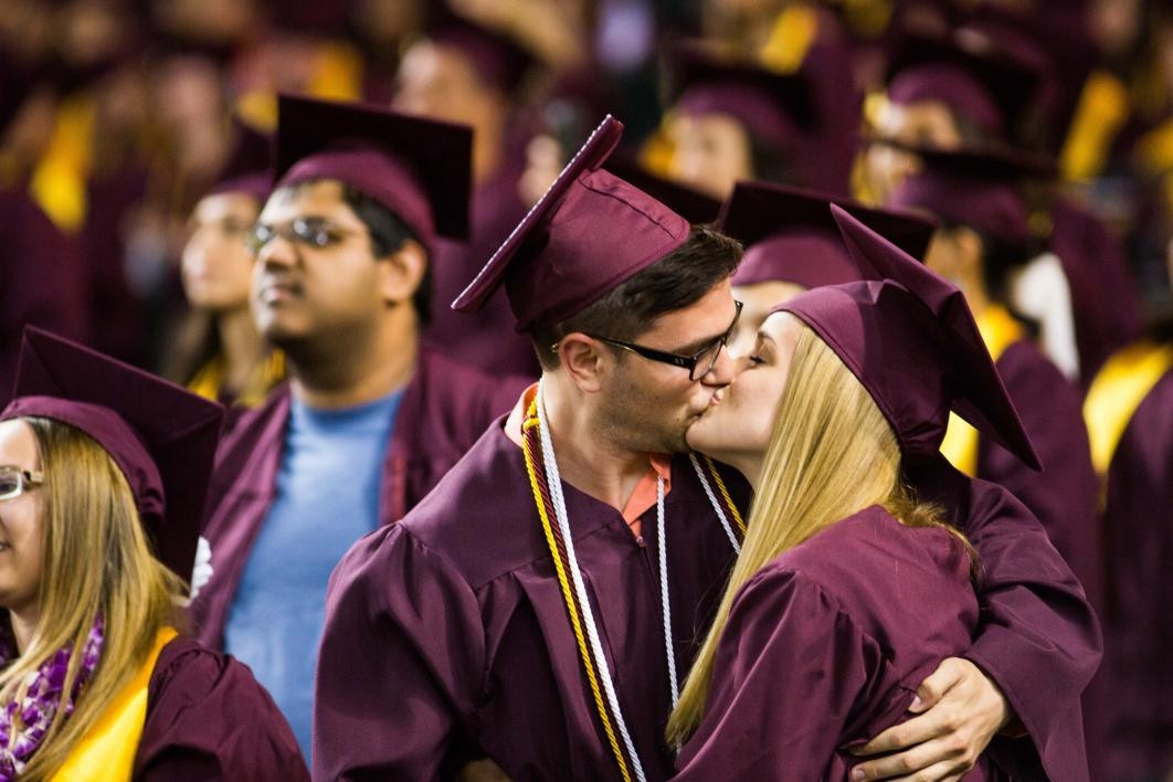 two grads kissing at commencement