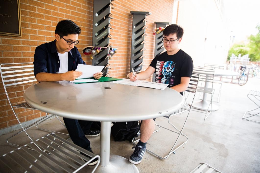 two students sitting outside at table