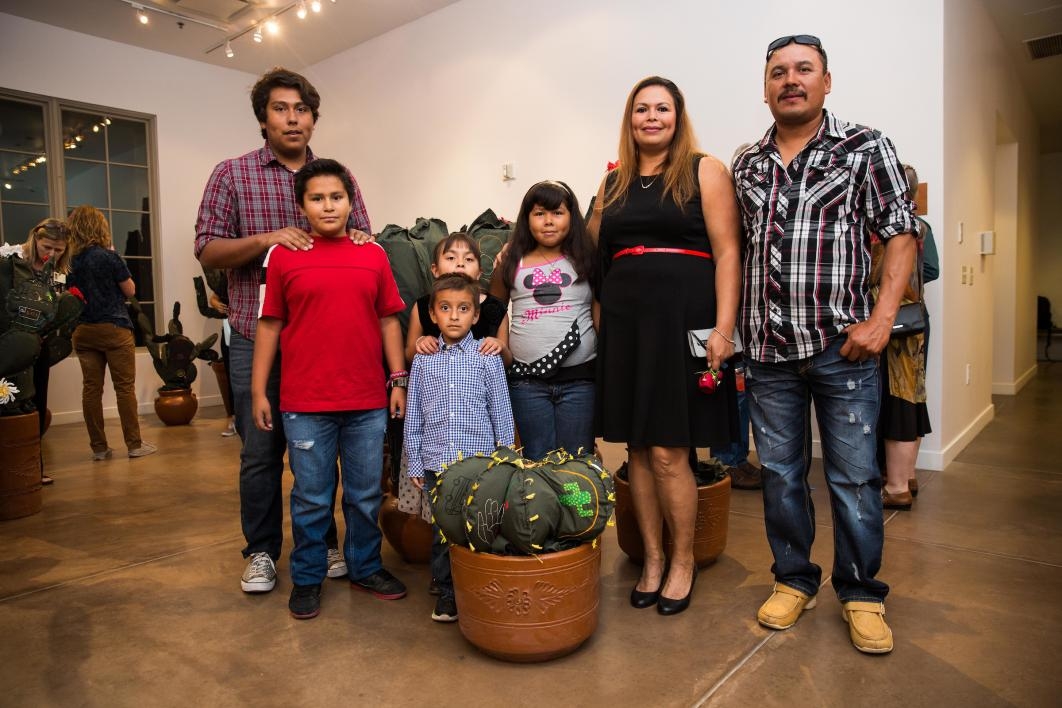 A family poses with a cloth cactus embroidered with their immigration story.