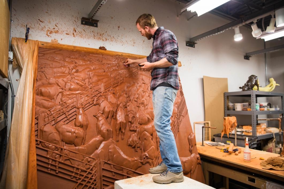 Artist Elliott Kayser works on a large-scale ceramic carving