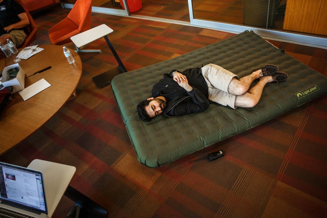 A staffer naps on an inflatable mattress during the hackathon