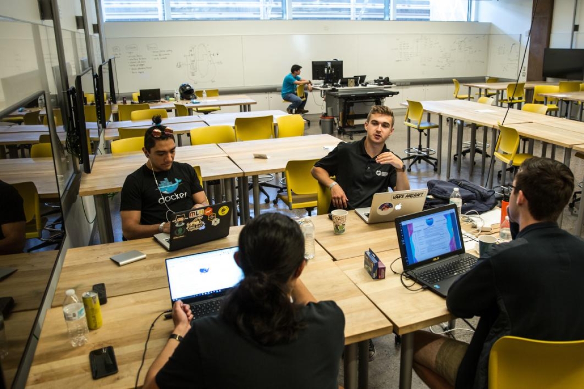 Students work around a table at a hackathon
