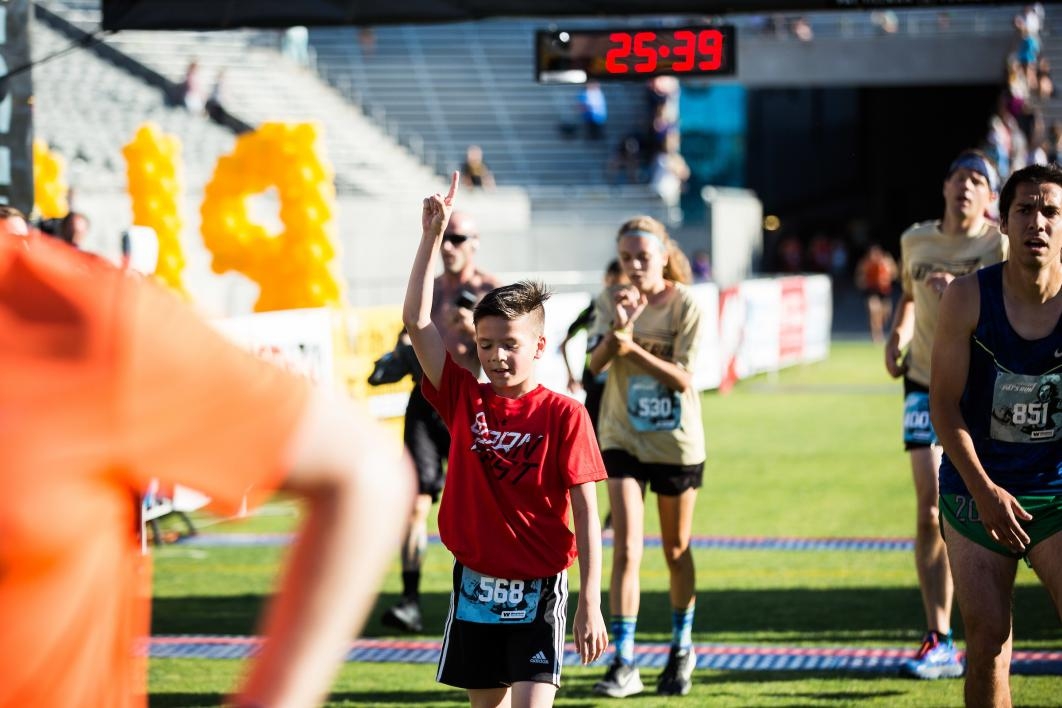 A boy is the first kid to cross the finish line at Pats Run