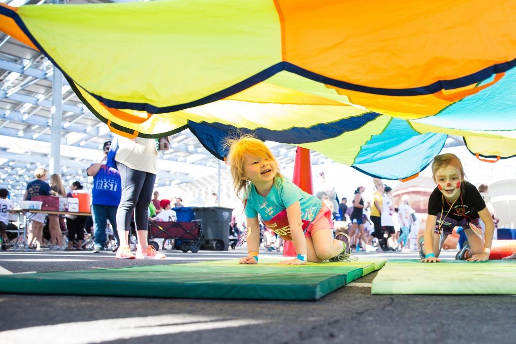 Little kids play under a parachute tarp at Pats Run