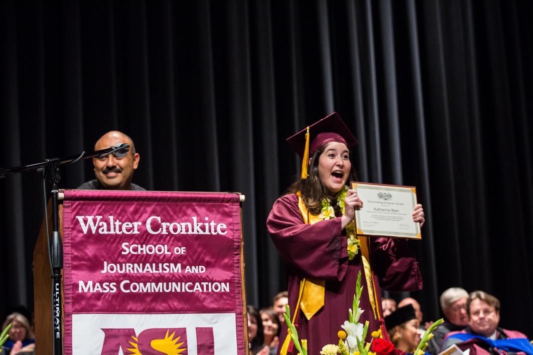 graduate holding up an award