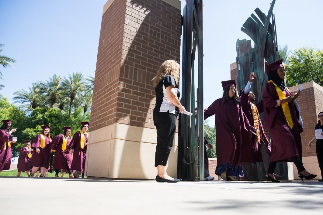 graduates passing through West campus gates