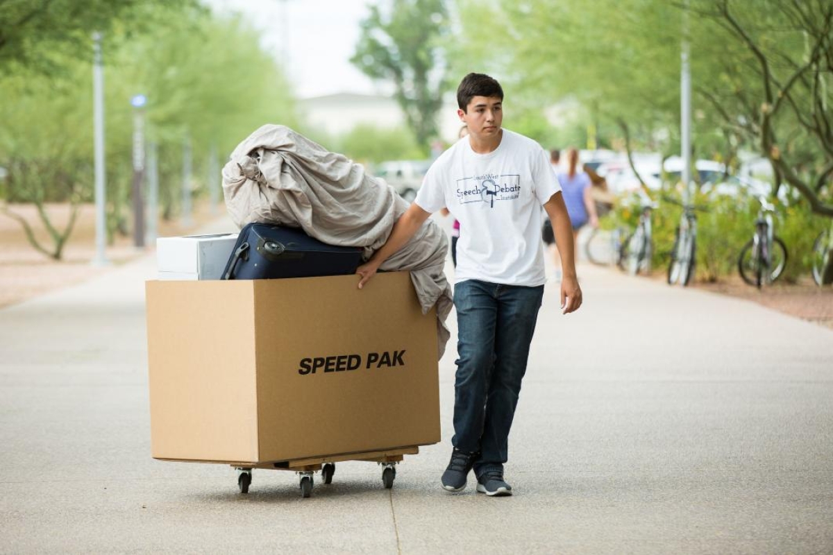 A student rolls his belongings across the Polytechnic campus during move-in