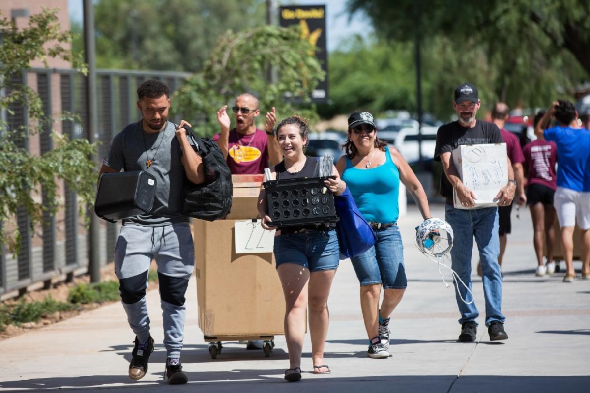 A family carries in belongings during move-in