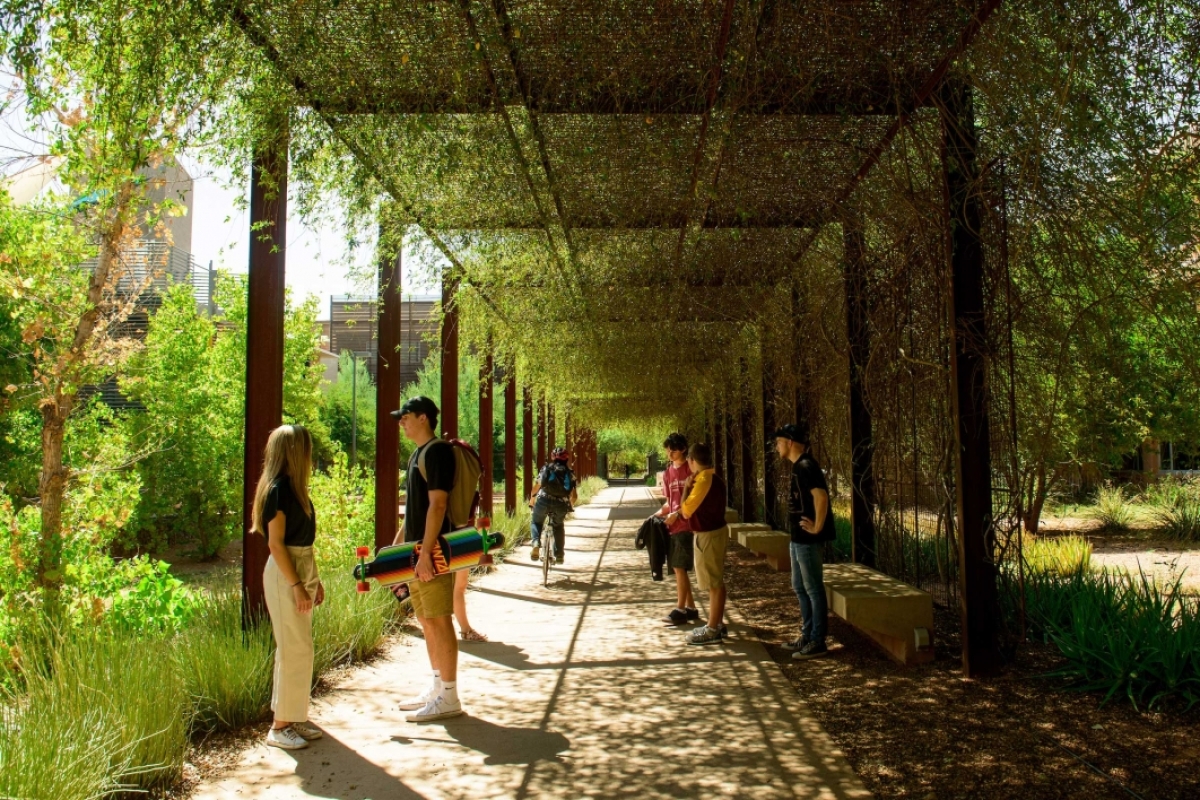 People gather beneath an outdoor arbor on the Polytechnic campus