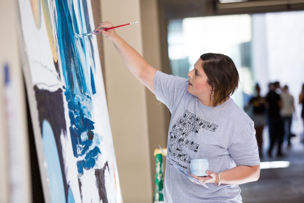 A woman paints a mural during Herberger Institute Day