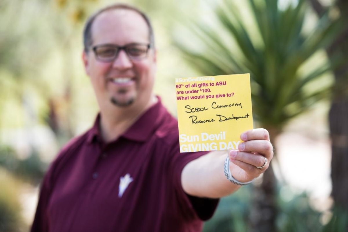 man holding post-it note saying: 92% of all gifts to ASU are under $100. What would you give to? School Community Resource Development
