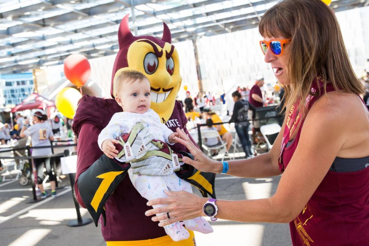 Sparky mascot holding a baby