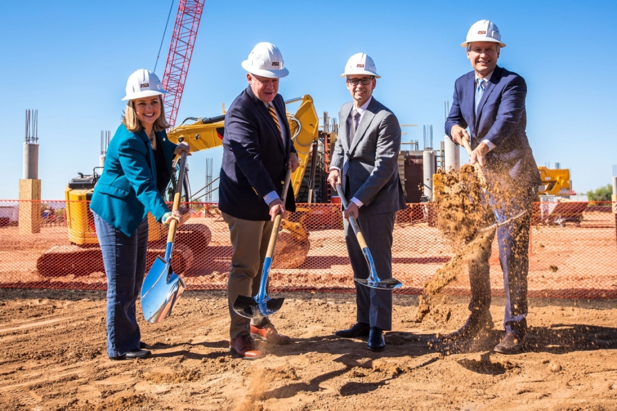 Four people turn over shovels of dirt at a ground breaking for the ASU Health Futures Center