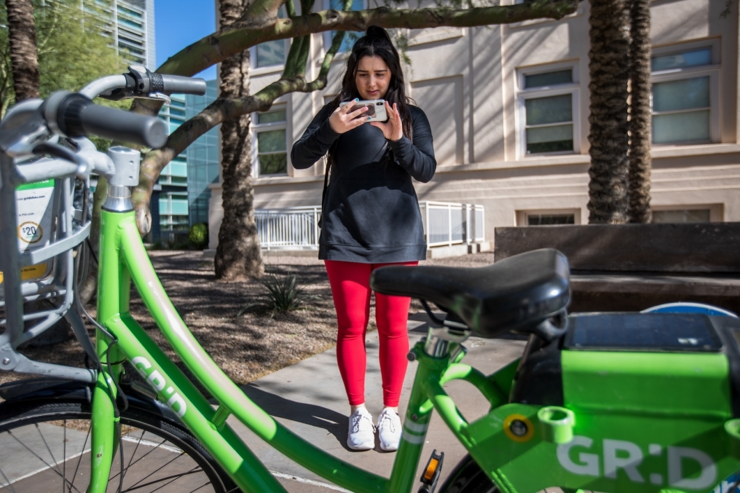 woman taking a photo of a ride-share bike with her smartphone