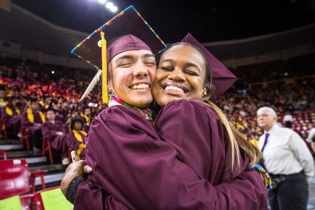 two graduates hugging