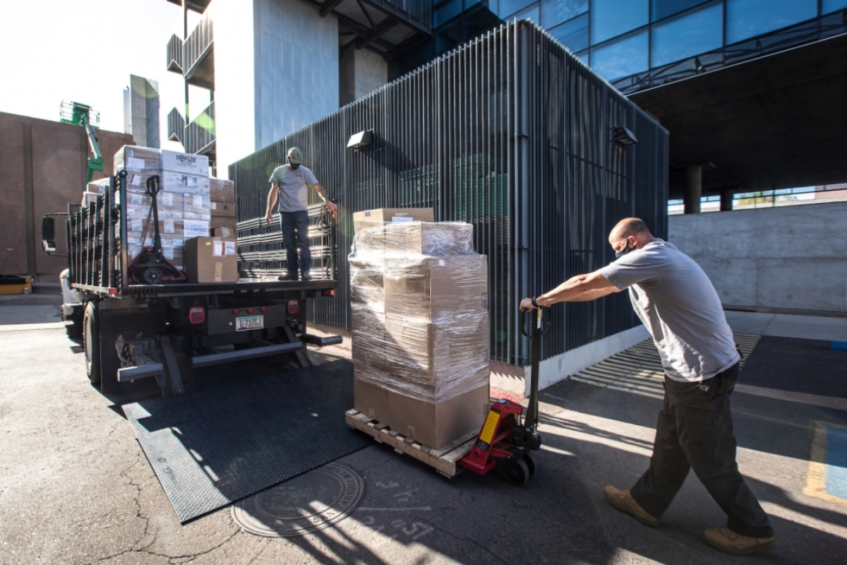 Men unload pallets of boxes of computer equipment from a truck
