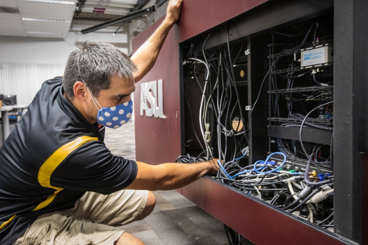 A man looks through an AV cabinet full of cables