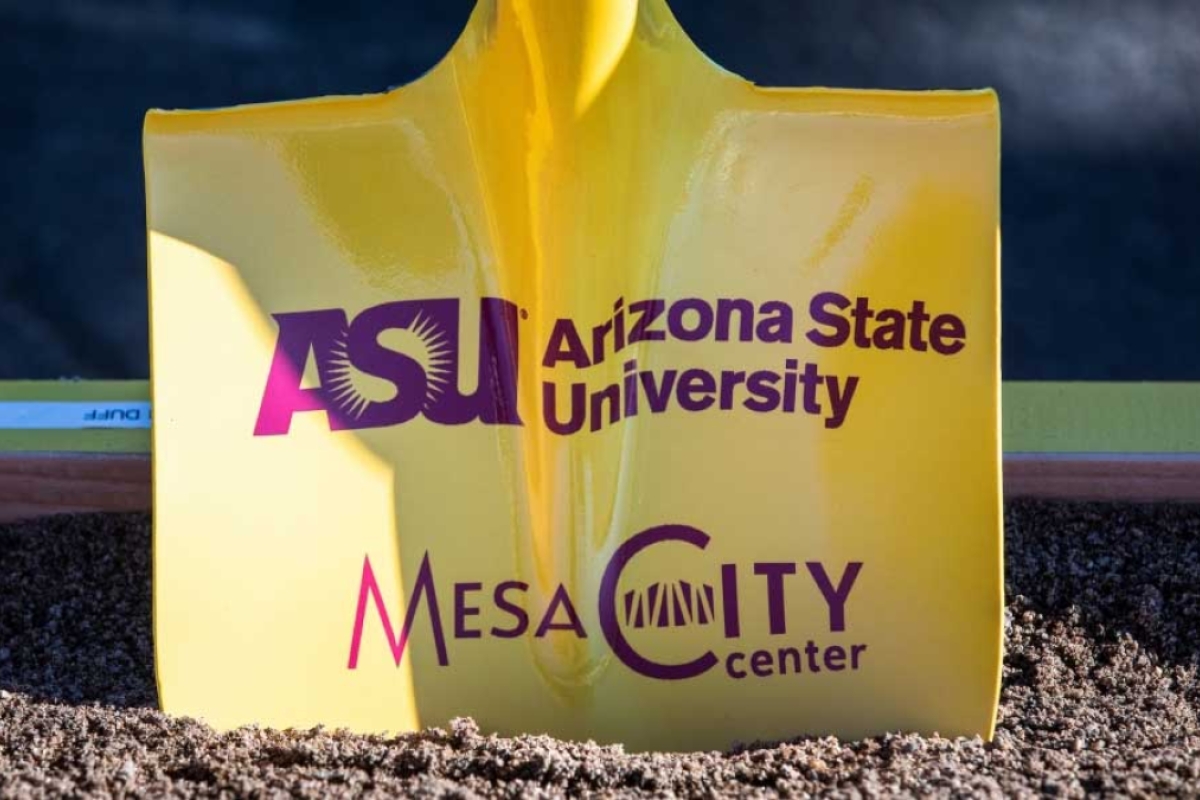 A yellow shovel in dirt with wording about ASU and the Mesa City Center in maroon