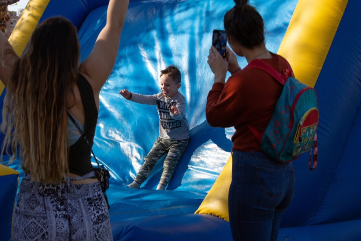 little boy slides down a blue inflatable slide