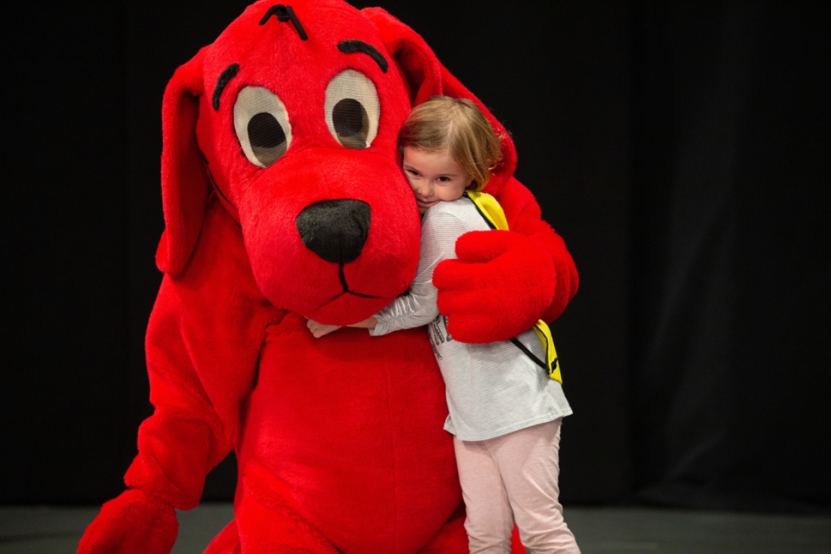 little girl hugs a Clifford the big red dog character